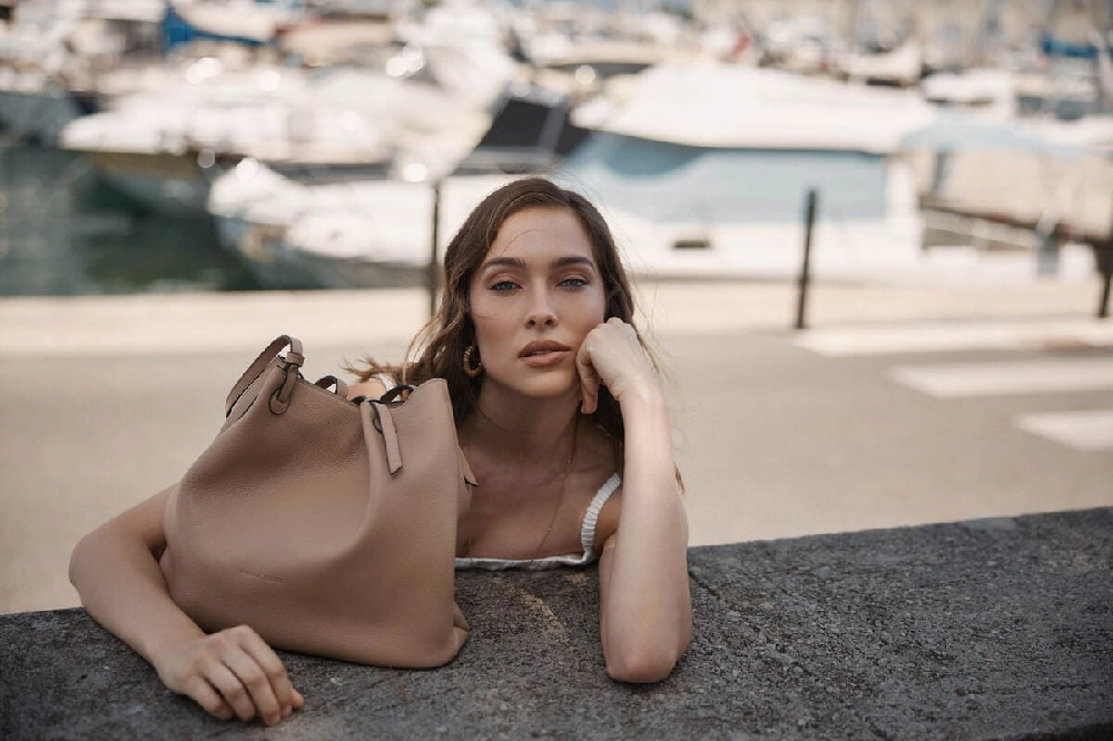 femeie care se sprijină pe cot cu o geantă alături